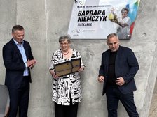 Barbara Niemczyk po odsłonięciu pamiątkowej tablicy z wręczoną ramką z mniejszą wersją tablicą