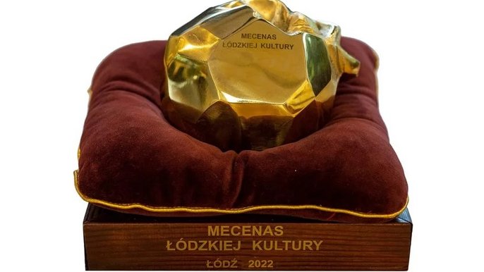 - W centralnym punkcie znajduje się duże, metalowe, błyszczące jabłko z napisem "Mecenas łódzkiej kultury". Jest to statuetka dla wyróżnionego.