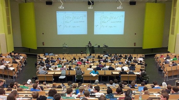 Sala wykładowa na uniwersytecie wypełniona studentami. Za pomocą rzutnika na ścianie wyświetlane są skomplikowane wzory matematyczne. Sala wykładowa na uniwersytecie wypełniona studentami. Za pomocą rzutnika na ścianie wyświetlane są skomplikowane wzory matematyczne. - Sala wykładowa na uniwersytecie wypełniona studentami. Za pomocą rzutnika na ścianie wyświetlane są skomplikowane wzory matematyczne.