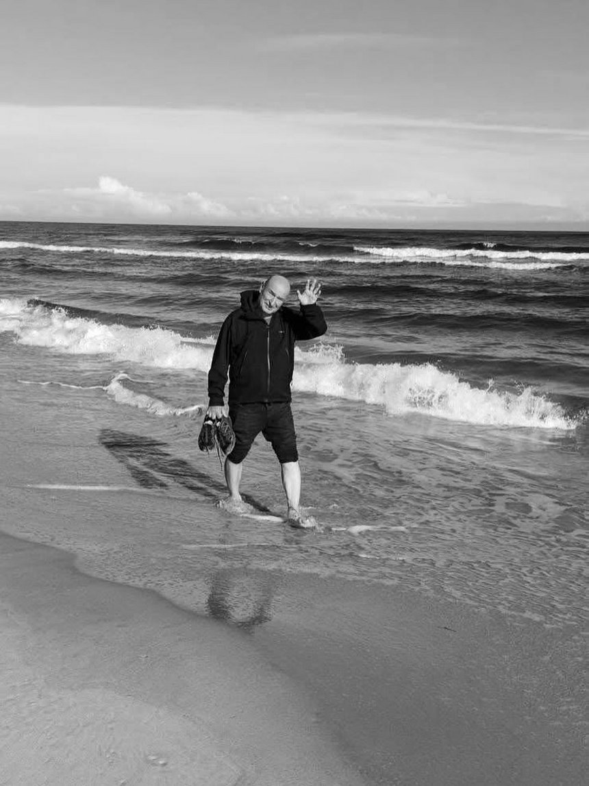na zdjęciu trener Marek Maciejewski spacerujący po plaży. Zdjęcie czarno-białe