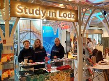 Stoisko pod hasłem "study in Lodz". Trzy kobiety w ciemnych bluzach.