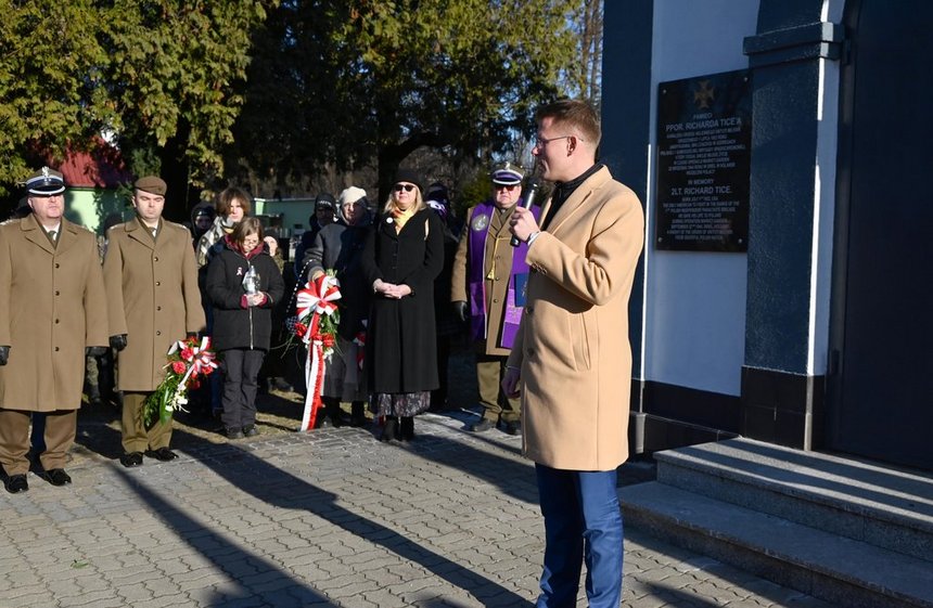 Wiceprezydent Łodzi Adam Wieczorek przemawia podczas uroczystości. Stoi przy wejściu do budynku - kaplicy. W tle uczestnicy uroczystości. Grupa około 10 osób, wśród nich żołnierze, młodzież i kapelan. 