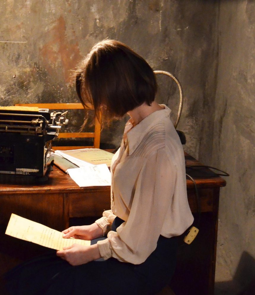 Anna Pałka, pracownica muzeum w rekonstrukcji więziennego przesłuchania. Kostium z zasobów Łódzkiego Centrum Filmowego. Fot: Artur Kamiński, Muzeum Tradycji Niepodległościowych w Łodzi