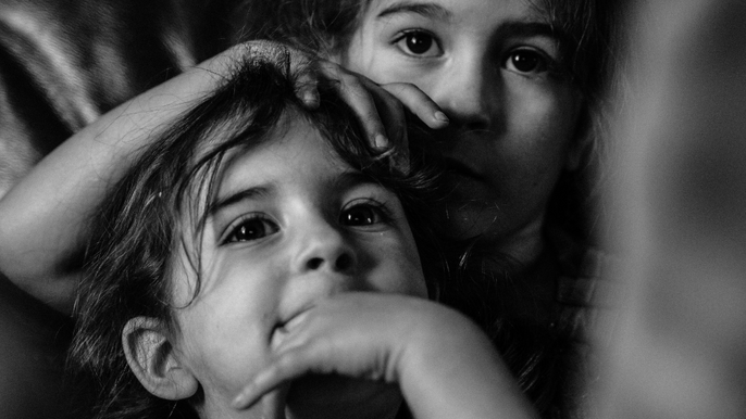  - Czarno-białe zdjęcie przedstawiające twarze dwójki kilkuletnich dzieci.