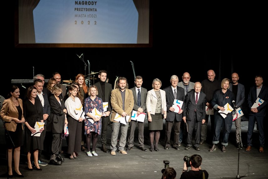 Na scenie teatralnej stoi grupa ludzi. W dłoniach trzymają listy gratulacyjne. Są to laureaci nagród.