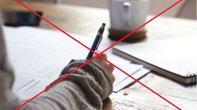 - Na pierwszym planie ręka trzymająca długopis nad dokumentami położonymi na biurku. Dalej kubek z ciepłym napojem. Grafika jest przekreślona czerwonym znakiem X.